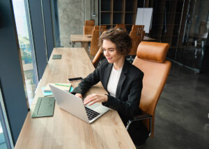 Portrait of corporate woman in suit, working in office, using laptop, typing, does her job in coworking space.