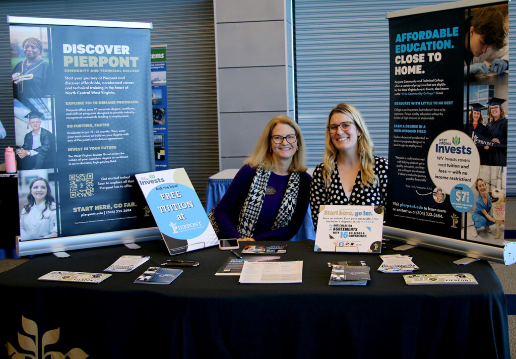 Nancy Parks and Jennifer McConnell sit behind a Pierpont Community & Technical College information table at the NCWV Business Summit.