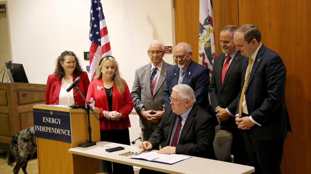 West Virginia Gov. Patrick Morrisey signs House Bill 5381 into law during a ceremonial bill signing at Pierpont Community & Technical College in Clarksburg, W.Va., joined by state senators and representatives who supported the legislation.