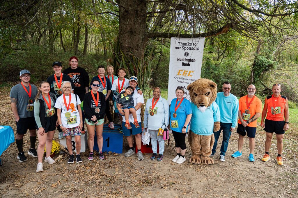 Participants gather for a group photo with Monty the Lion and Dr. Michael Waide during the inaugural Fall in Love with Health 5K and Monty’s Mini Mile at Prickett’s Fort State Park in Fairmont, W.Va.