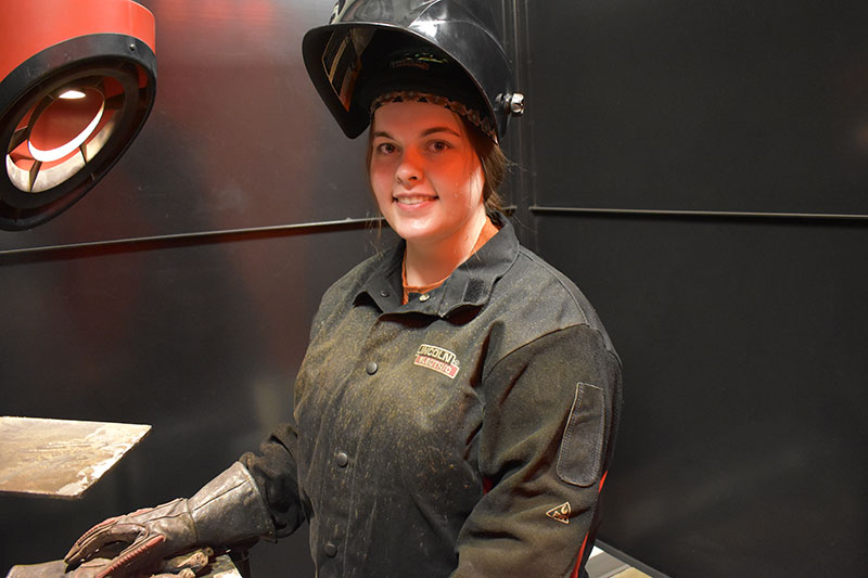 Welding student Ariel Mallow wearing welding shield and protective gloves