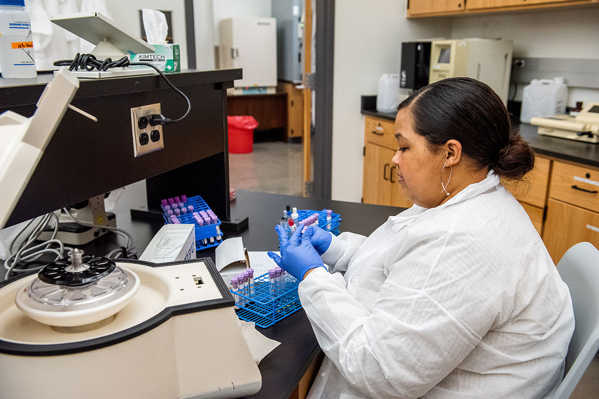 Woman in lab coat applies label to blood sample