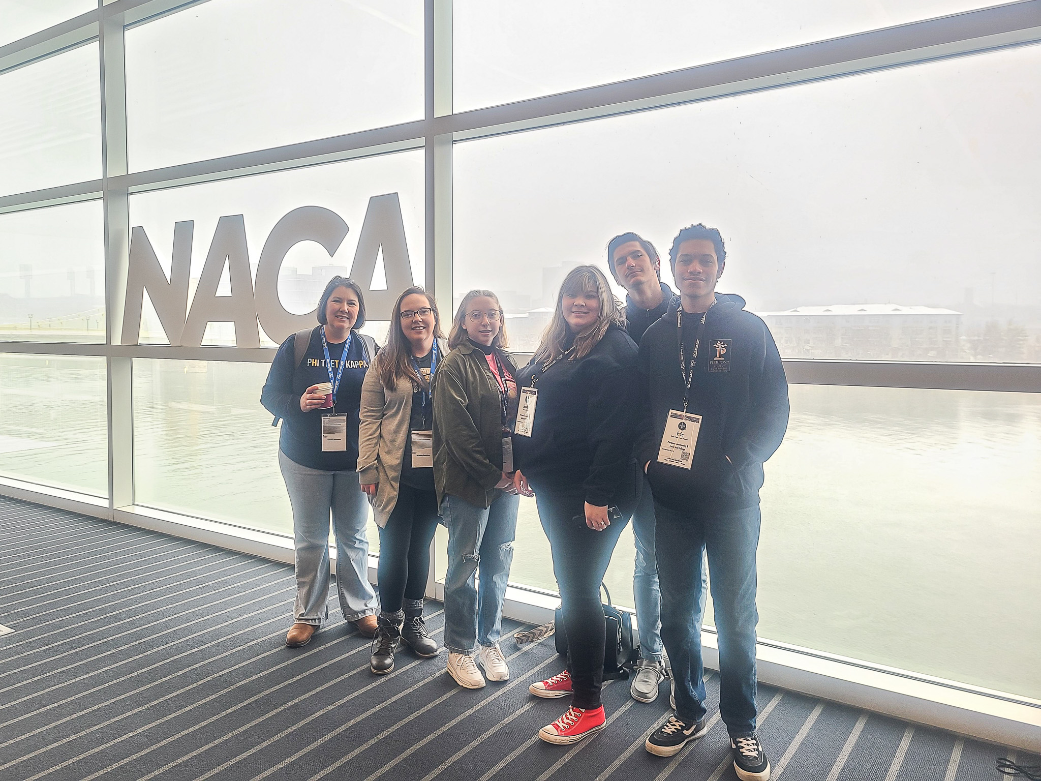 A group of students pose for a photo in front of a sign reading, "NACA."