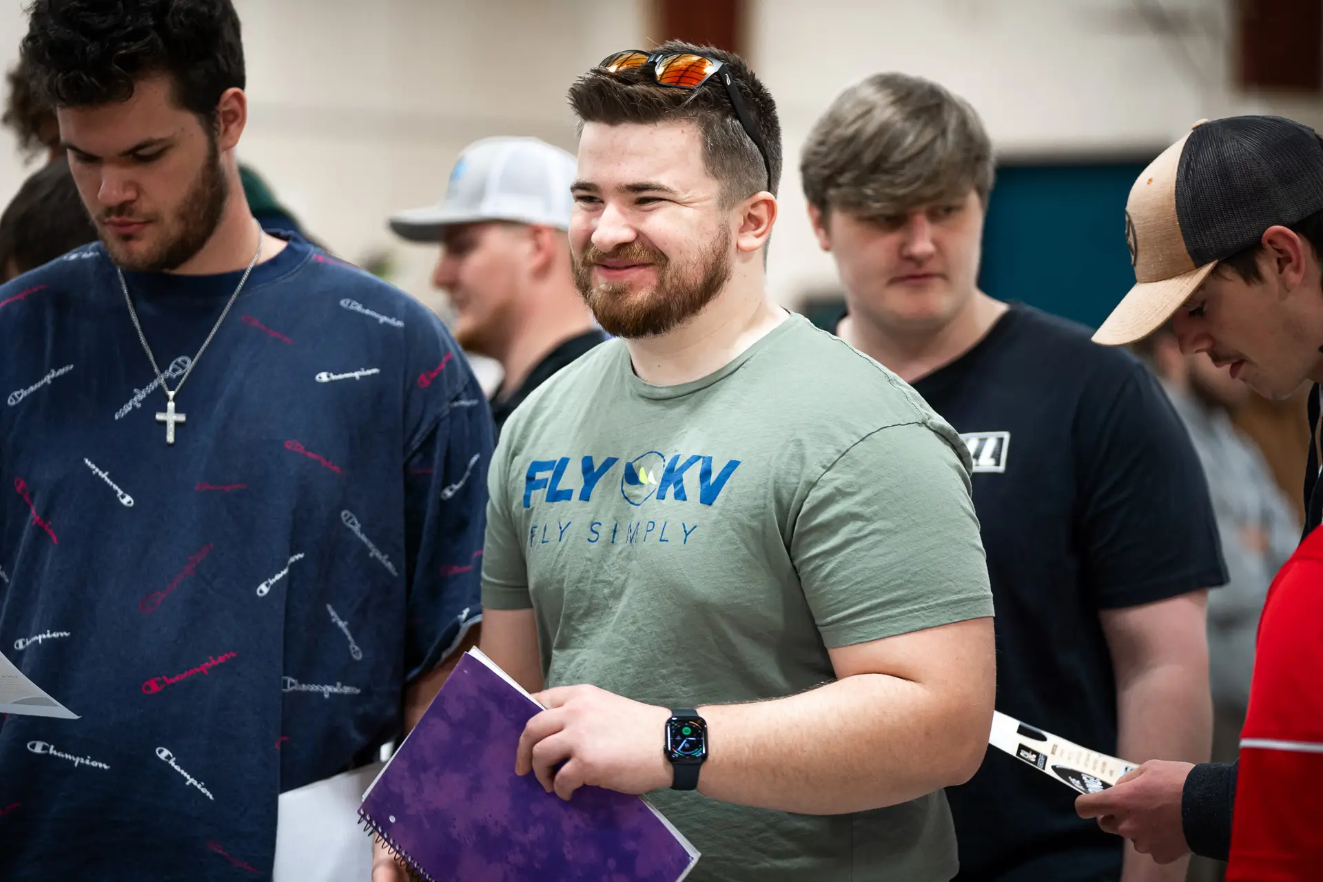 A student wearing a green shirt holds a notebook while in attendance at the Aviation Career Fair.