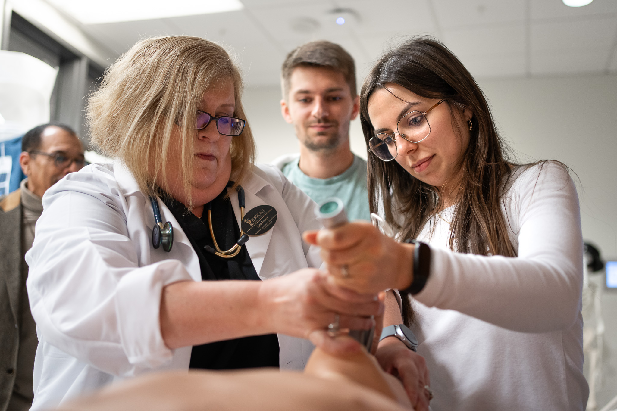 Two attendees work with Pierpont's health sciences faculty to practice intubation.