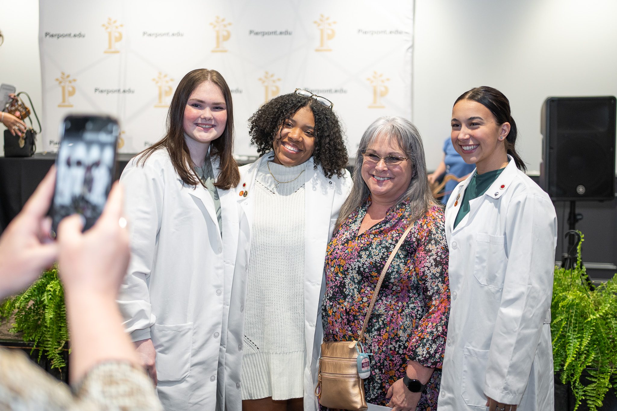 A group of four individuals smile for a photo following the ceremony. Three are wearing lab coats.