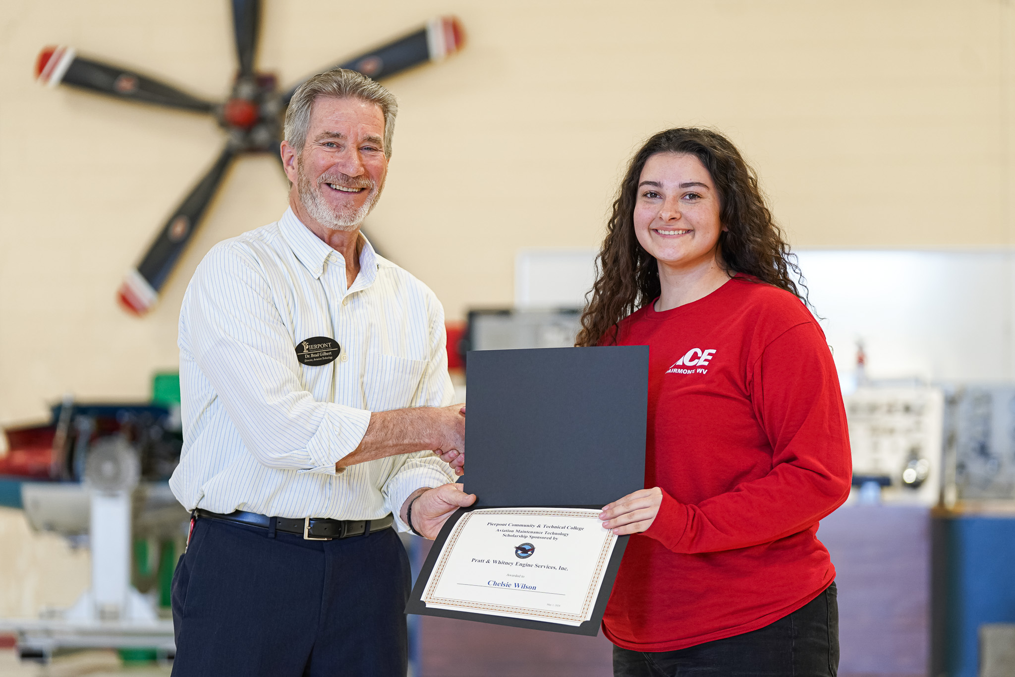 A student is pictured with Dr. Brad Gilbert accepting a scholarship certificate.