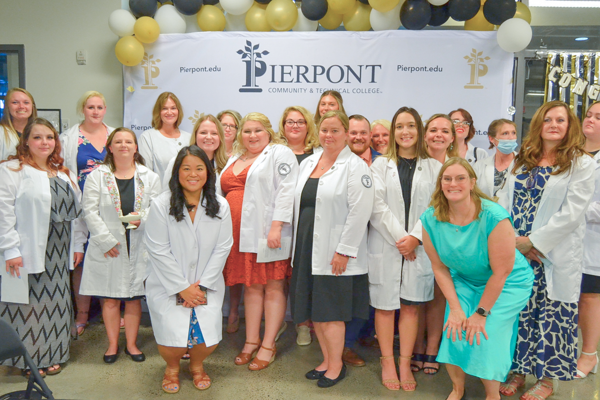 Students in Pierpont's licensed practical nursing program pose for a photo in front of a white Pierpont backdrop.