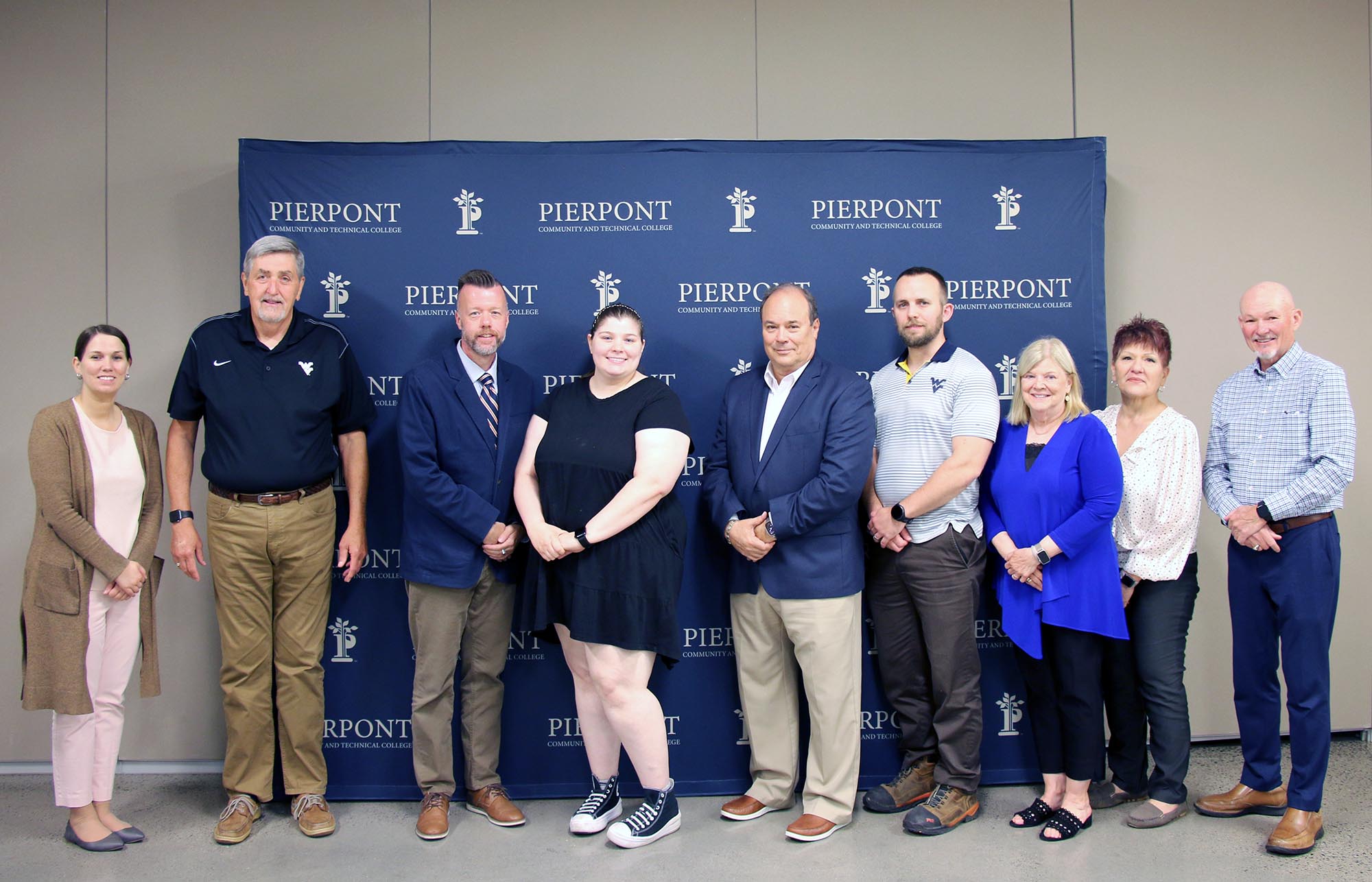 Board Members stand together at the Pierpont backdrop for a group photo.