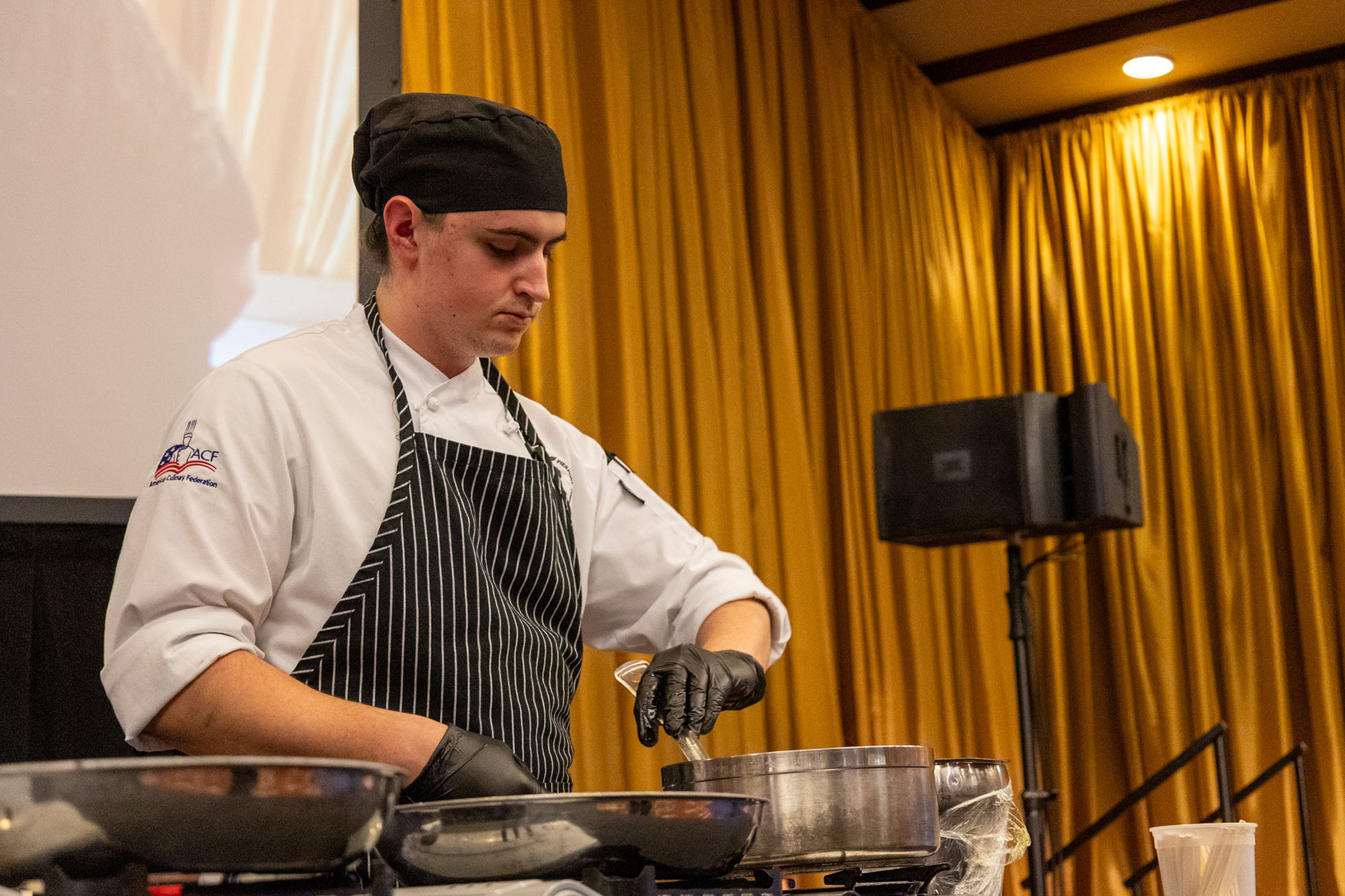 Concentration and precision on display as Matthias Freeman, a Food Service Management student at Pierpont Community & Technical College, finishes a component of his competition dish at the 3rd Annual WVU Culinary Competition at Nemacolin.