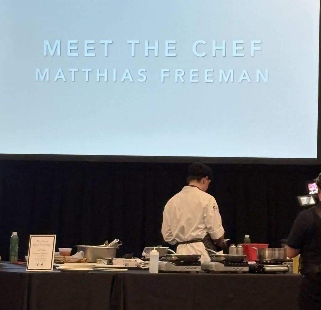 A screen introduces Pierpont culinary student Matthias Freeman during the 3rd Annual WVU Culinary Competition, where students were highlighted while preparing their competition dishes at Nemacolin.
